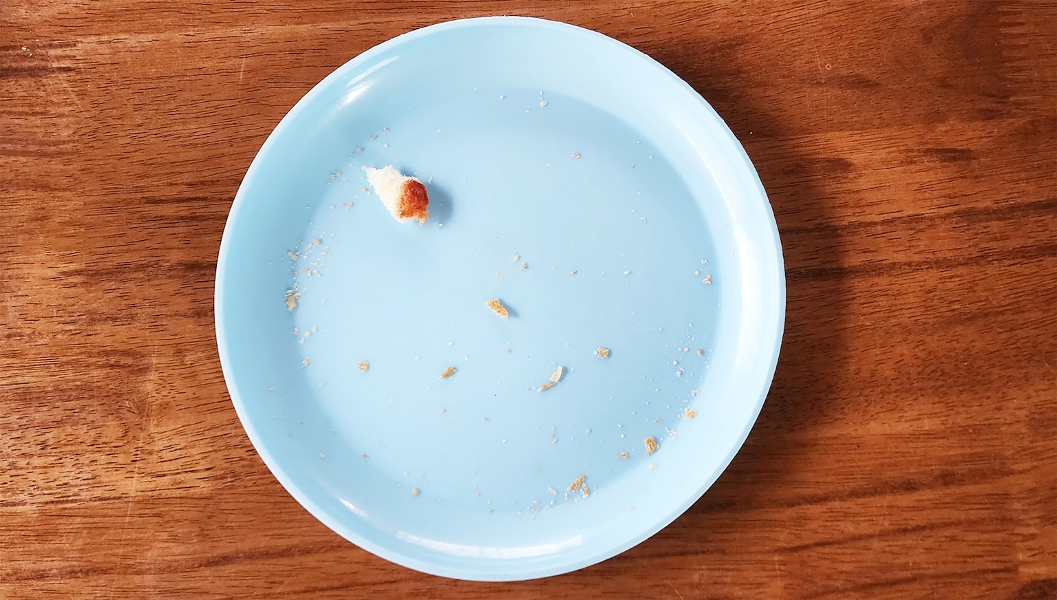 Piring biru muda dengan sisa makanan di atas meja kayu
