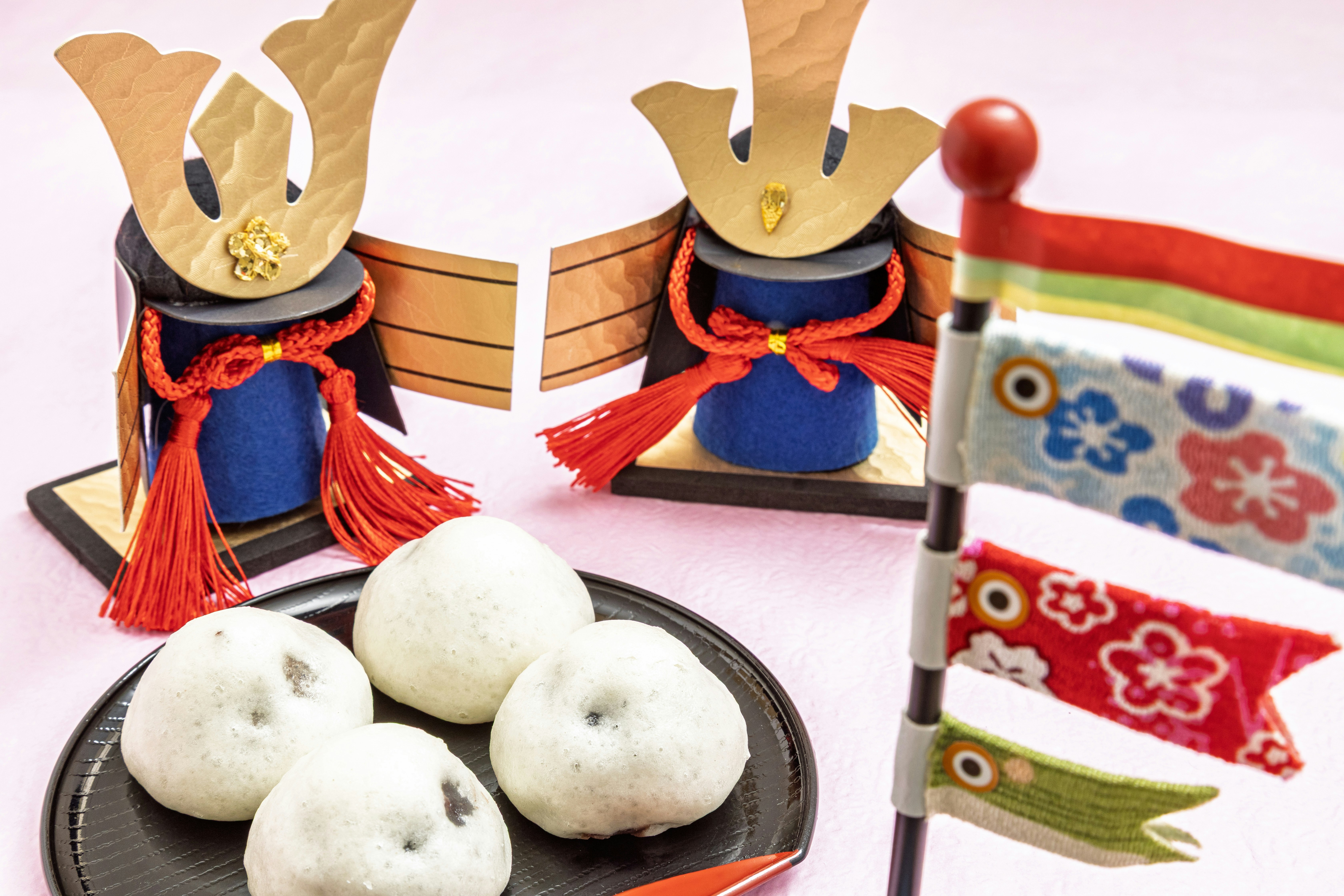 兜飾りと和菓子、国旗風の小旗が並ぶ端午の節句の卓上