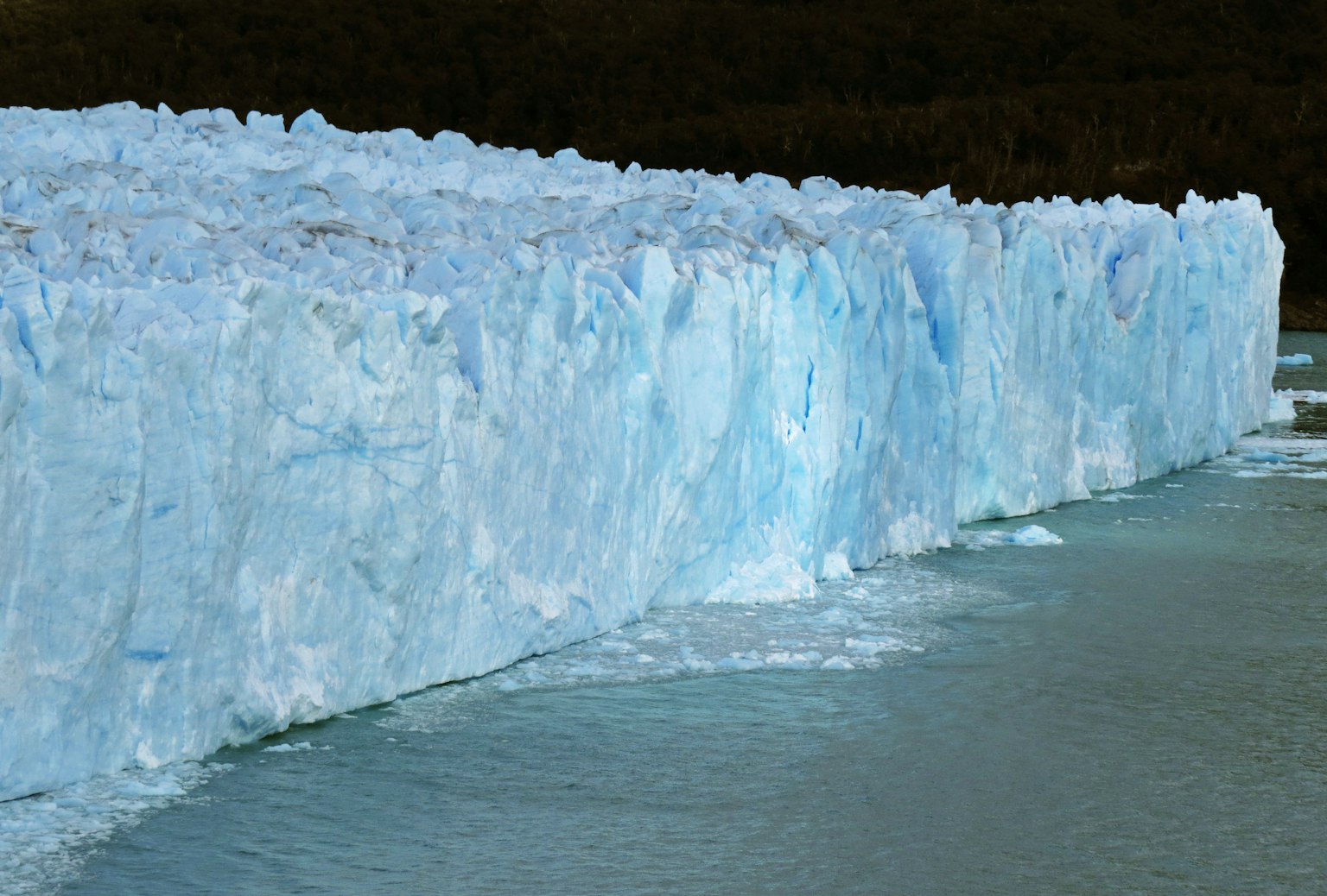 Mur de glace bleue d'un glacier avec des reflets dans l'eau