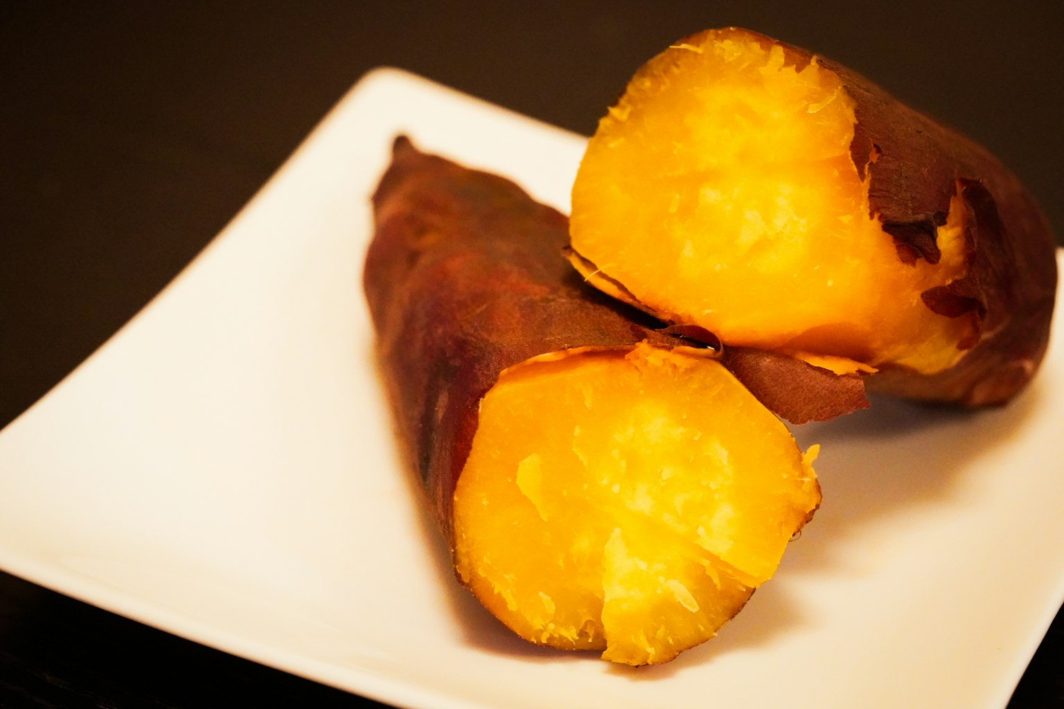 Patate douce cuite sur une assiette avec un extérieur brun et un intérieur jaune vif
