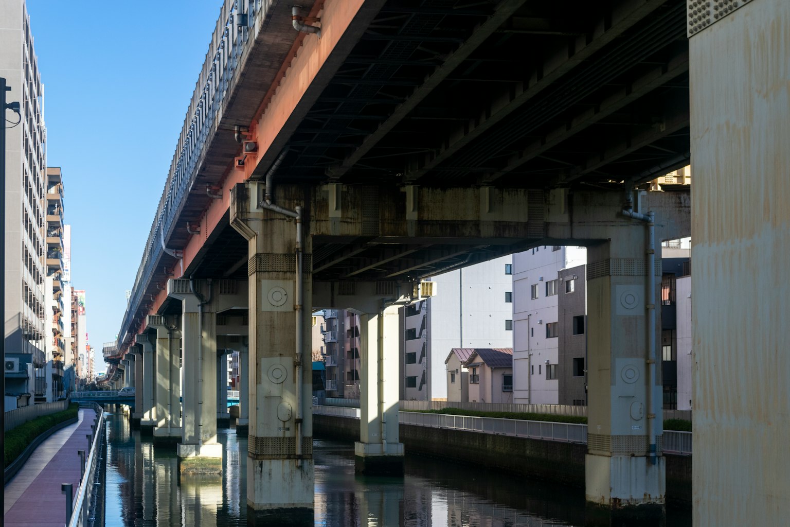 Pemandangan kanal dengan bangunan dan jembatan tinggi di atas