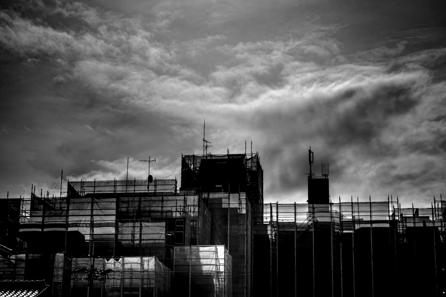 Silueta de un edificio en construcción con nubes oscuras