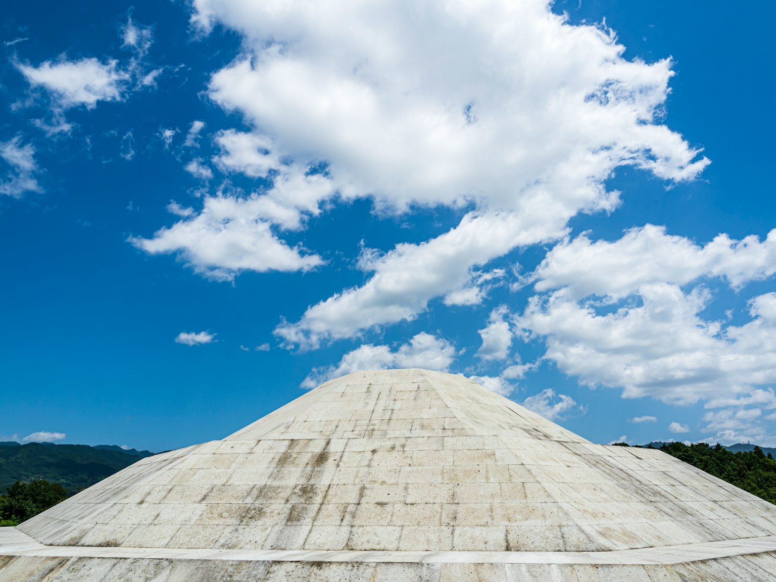 Struttura a piramide in cemento sotto un cielo blu chiaro