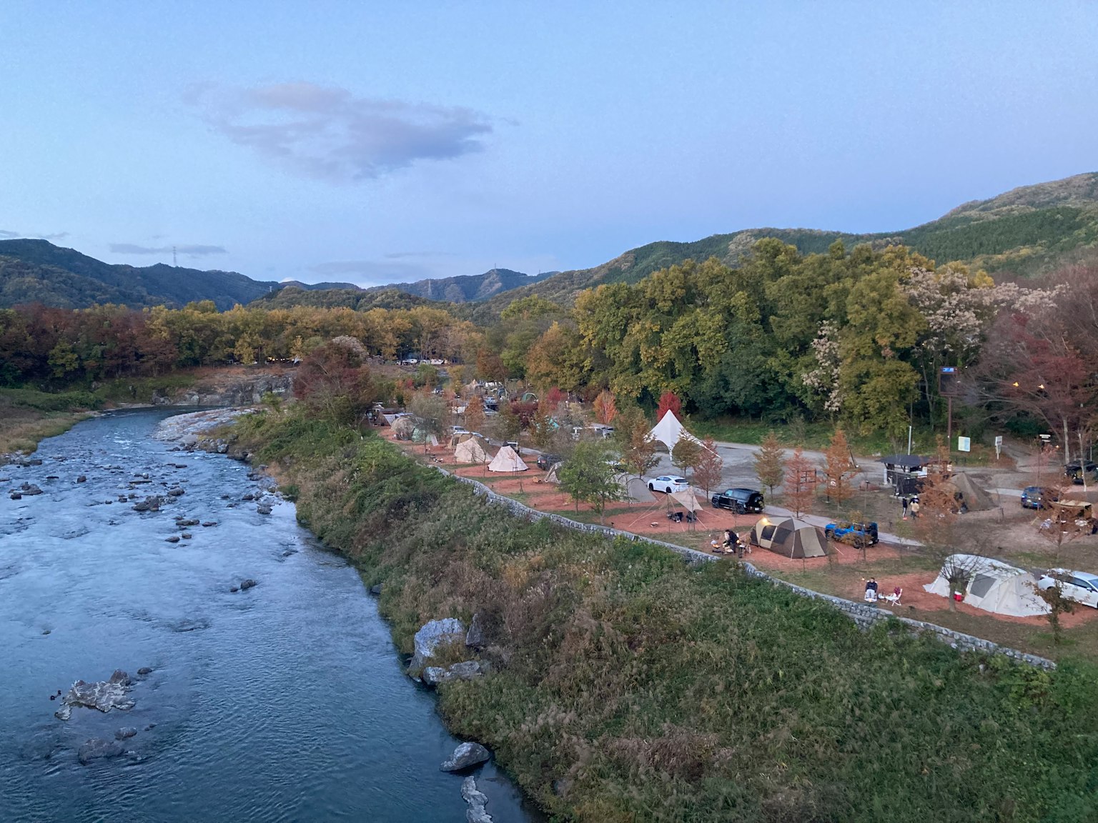 Un campeggio a bordo fiume con alberi colorati sullo sfondo