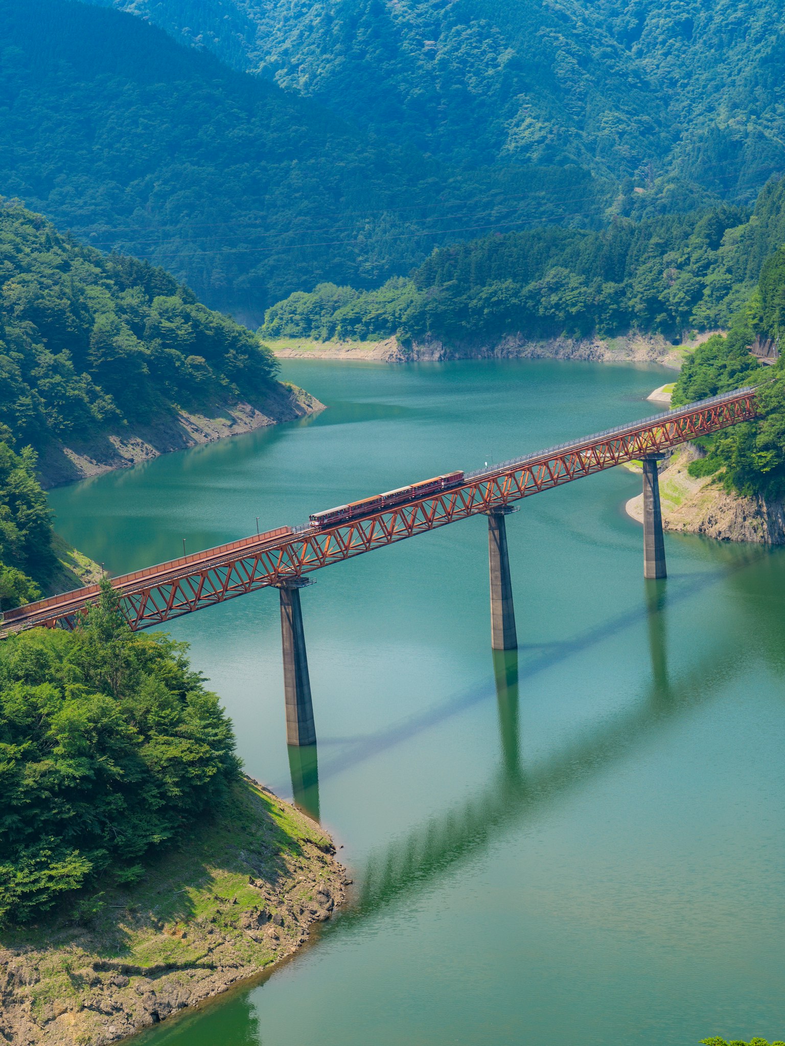 Un pont ferroviaire enjambant une rivière entourée de montagnes verdoyantes