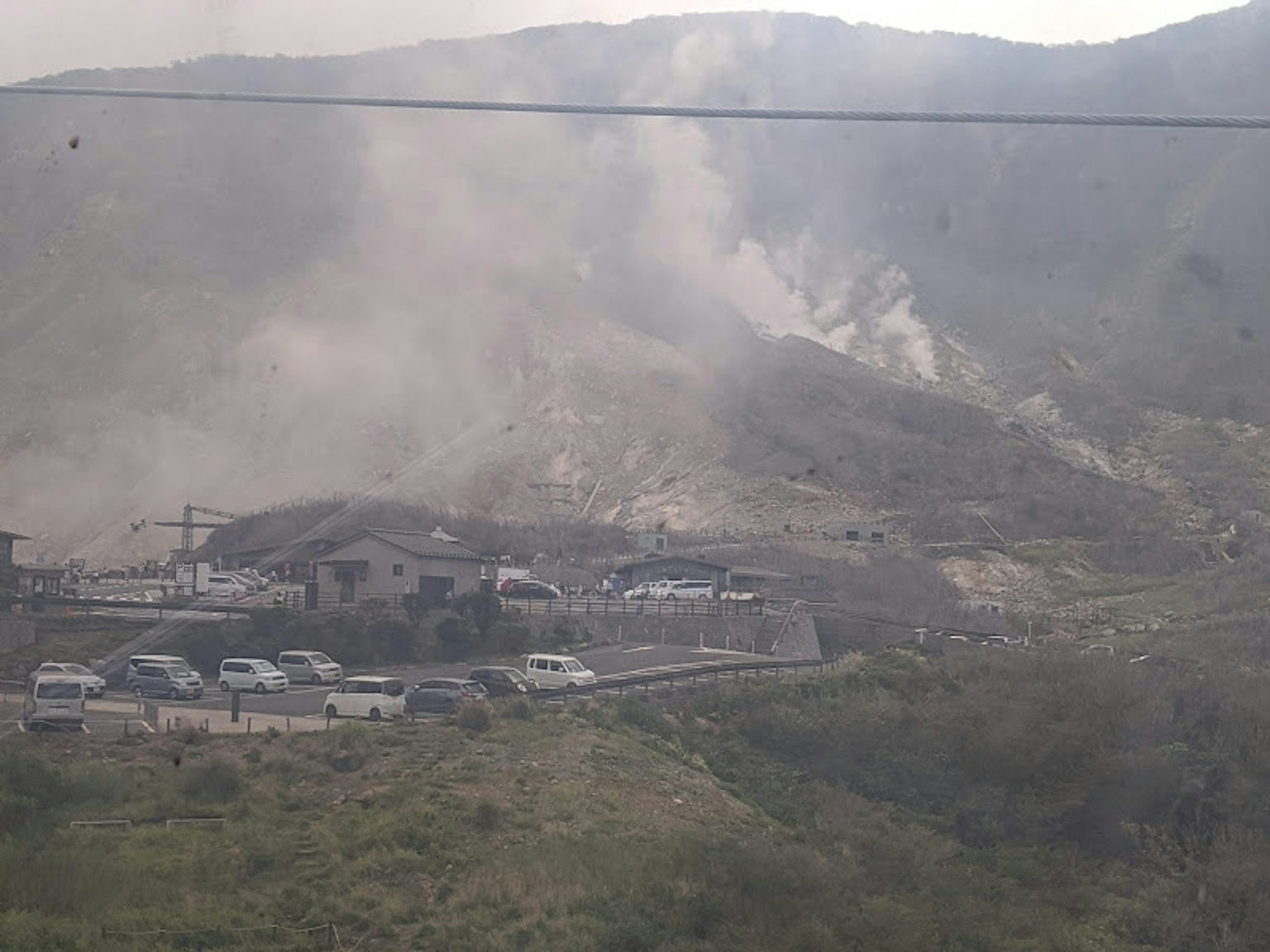 Landscape with smoke rising from mountains and parked cars