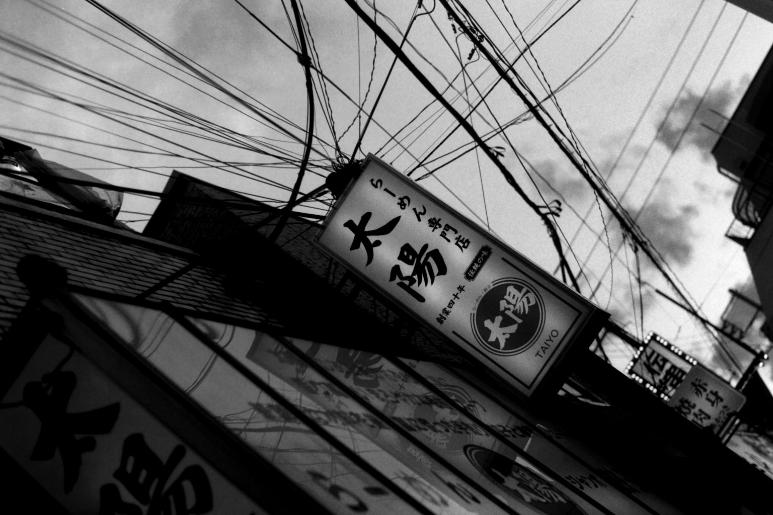 Scena urbana in bianco e nero con un'insegna e un complesso di linee elettriche