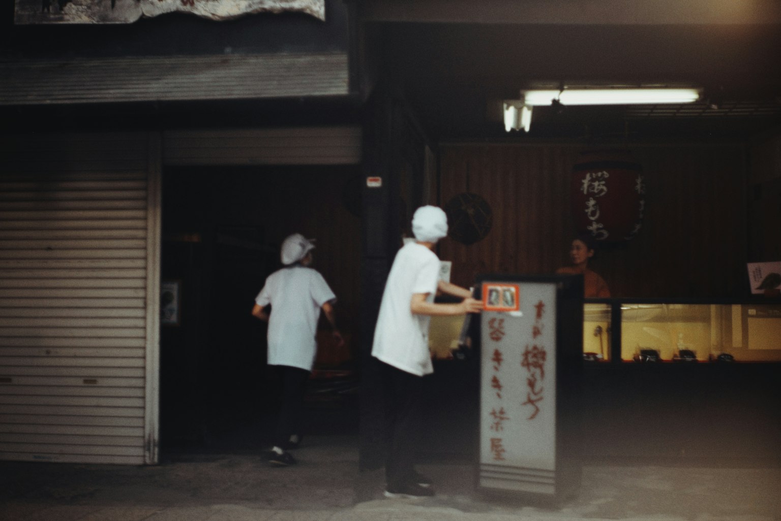 古い商店街の外観で白い服を着た二人の店員がいる