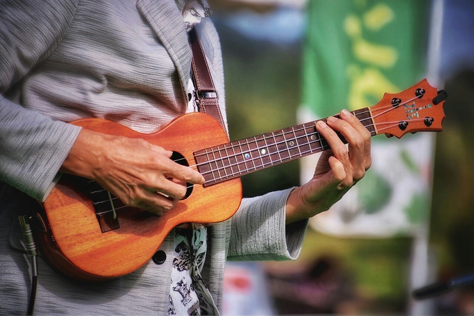 Pria yang memainkan ukulele dengan detail instrumen kayu