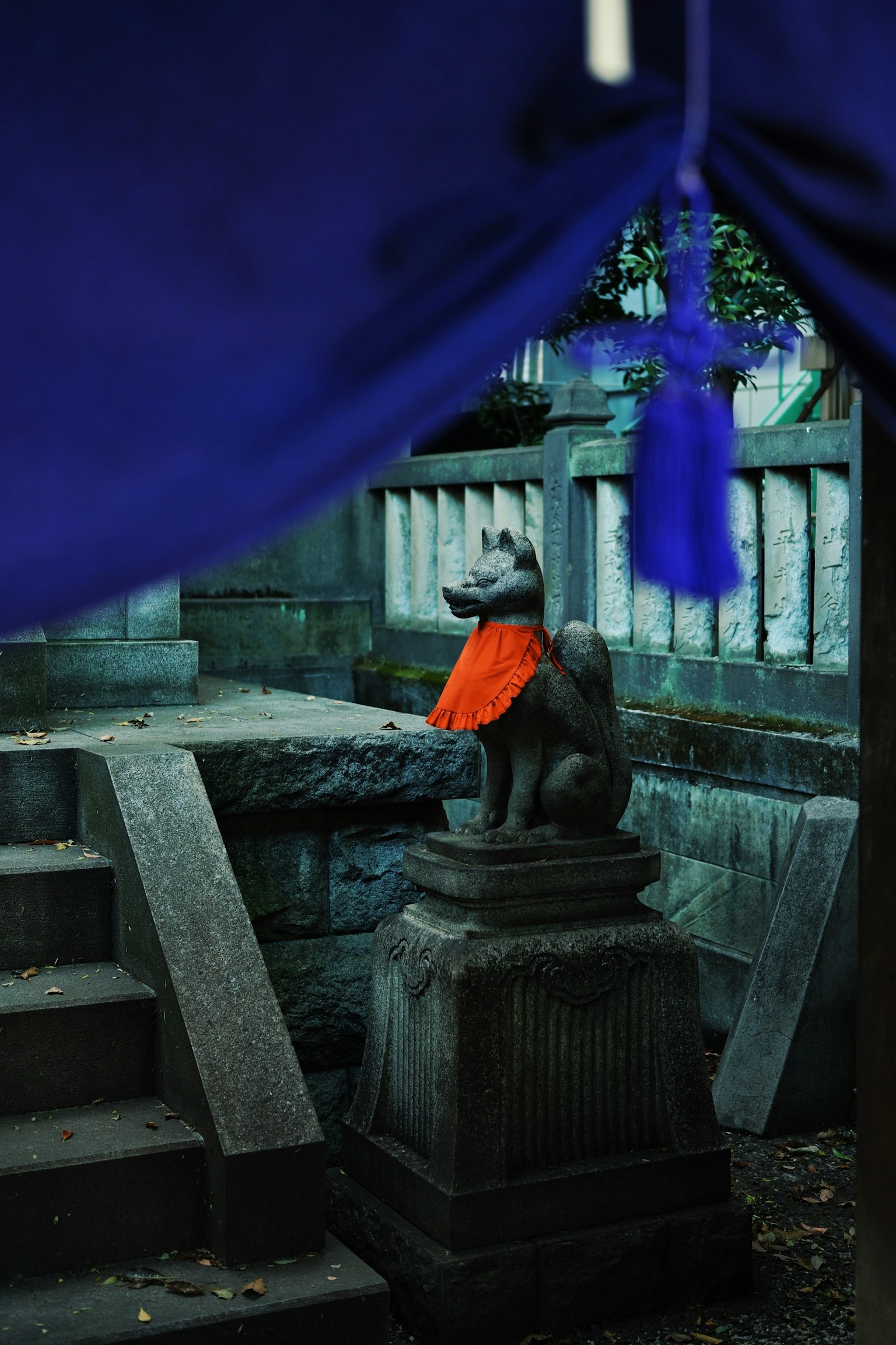 Statua in pietra di un leone guardiano con una sciarpa arancione sotto un tessuto blu