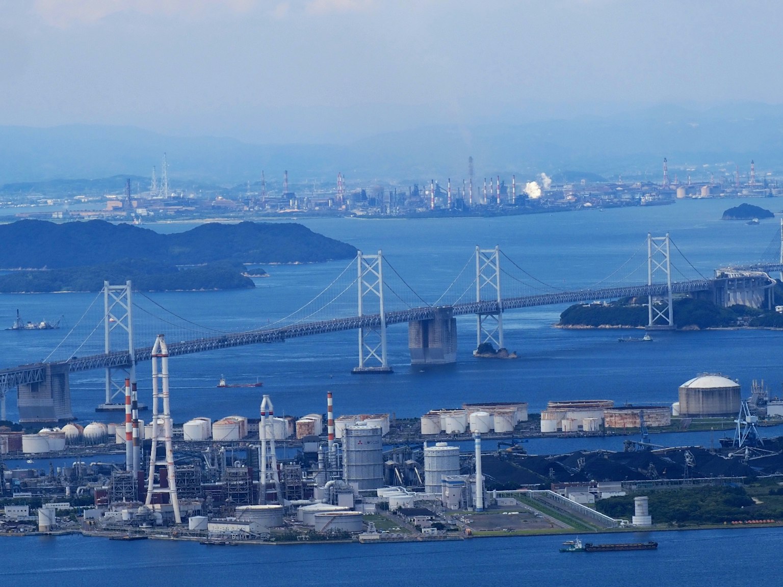 Vista aerea di un ponte su acque blu con strutture industriali