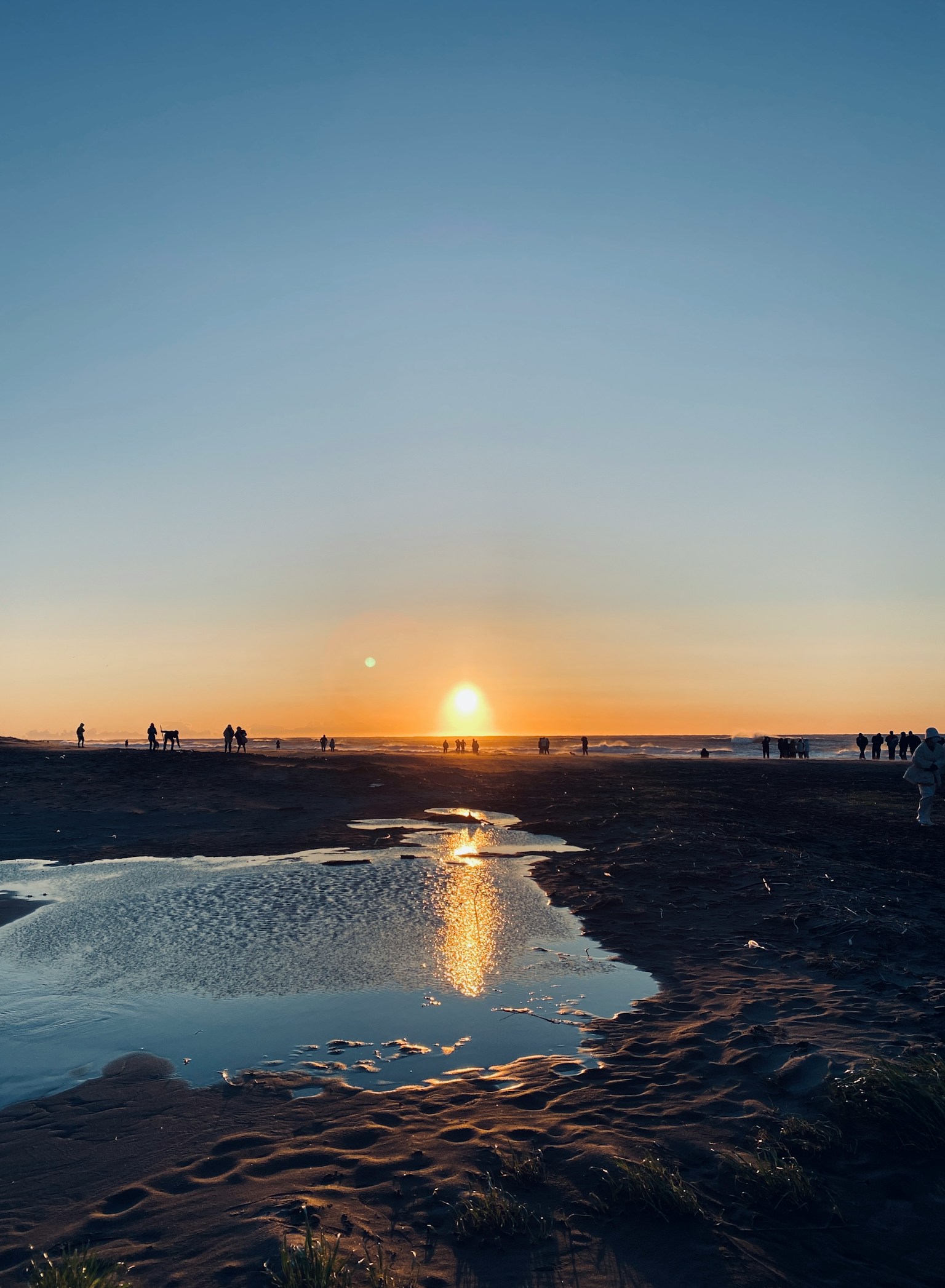 Sunset over the beach with silhouetted people in the distance
