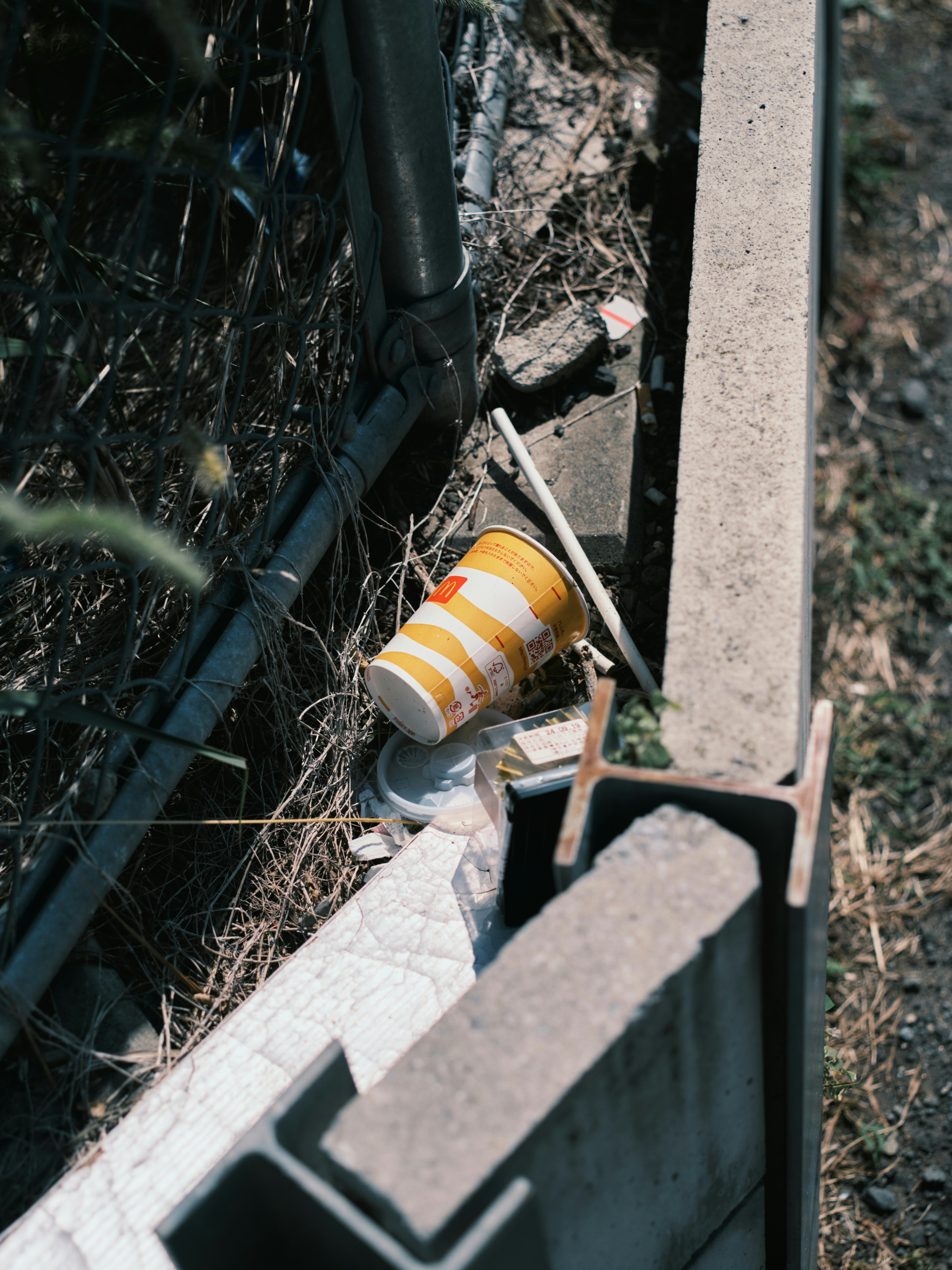 suelo con una botella amarilla y basura cerca del bambú