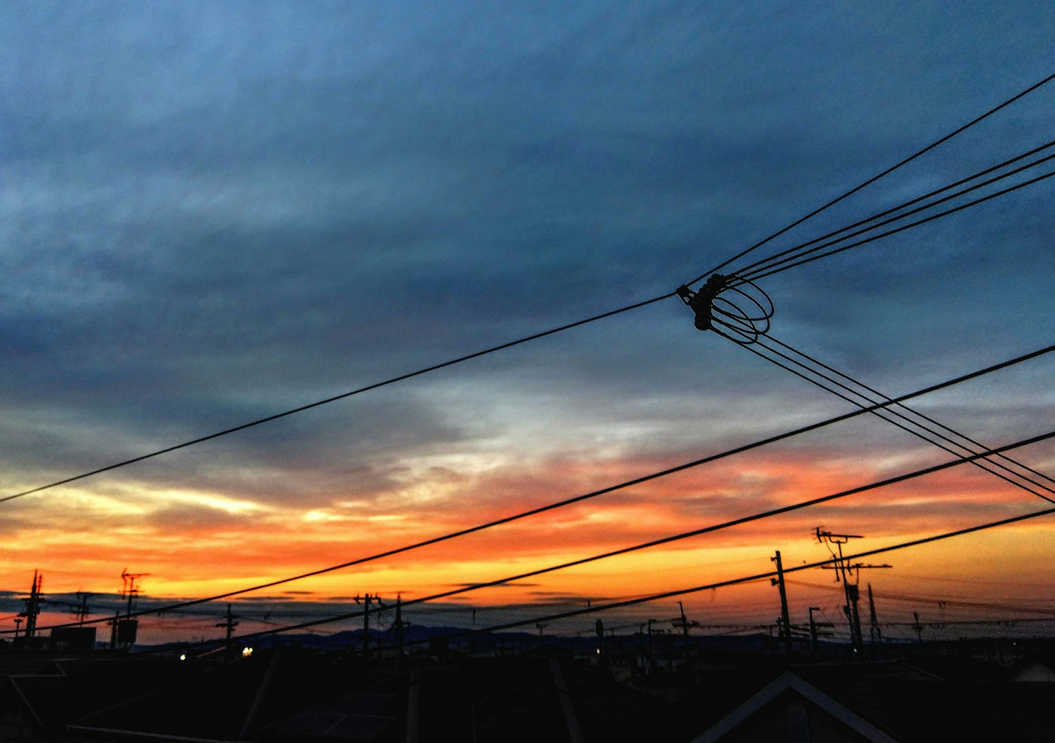 Farbenfroher Sonnenuntergangshimmel mit sich kreuzenden Stromleitungen