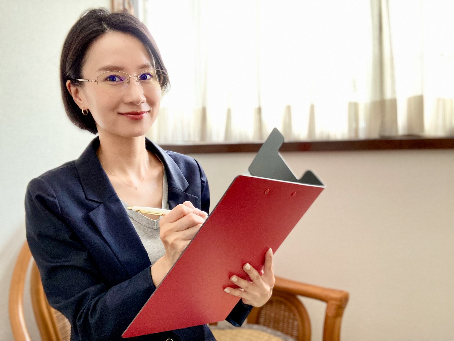 Une femme souriante tenant un clipboard rouge dans un bureau