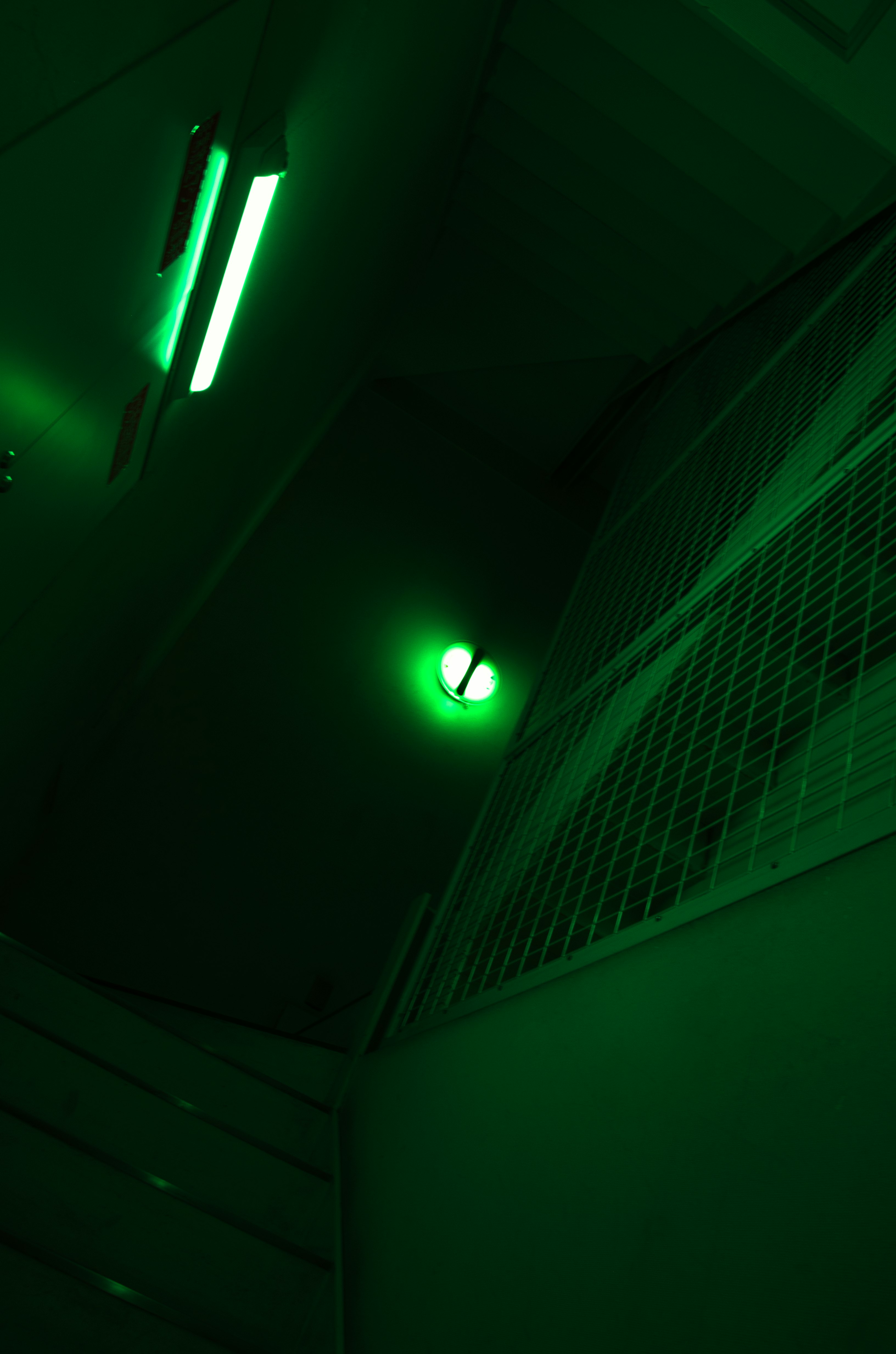 綠色霓虹燈照亮的昏暗走廊與網格牆
