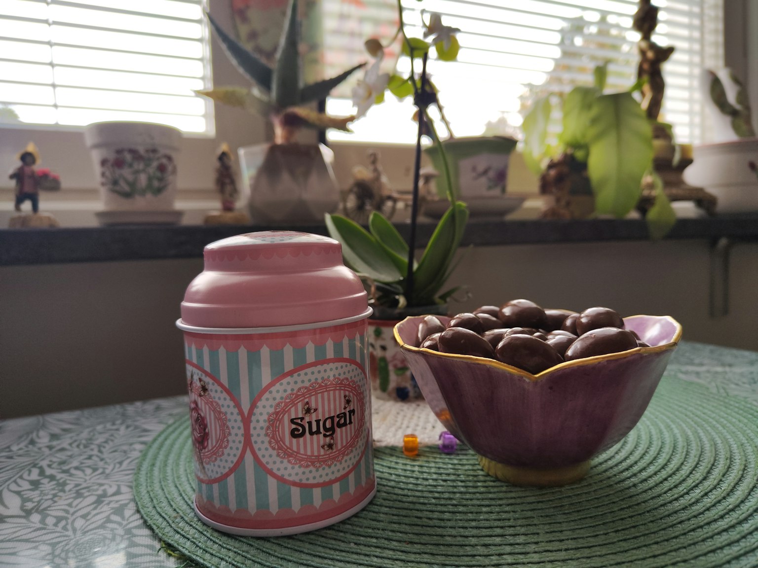 Sebuah kaleng pink dan mangkuk ungu berisi permen di atas meja dalam ruangan
