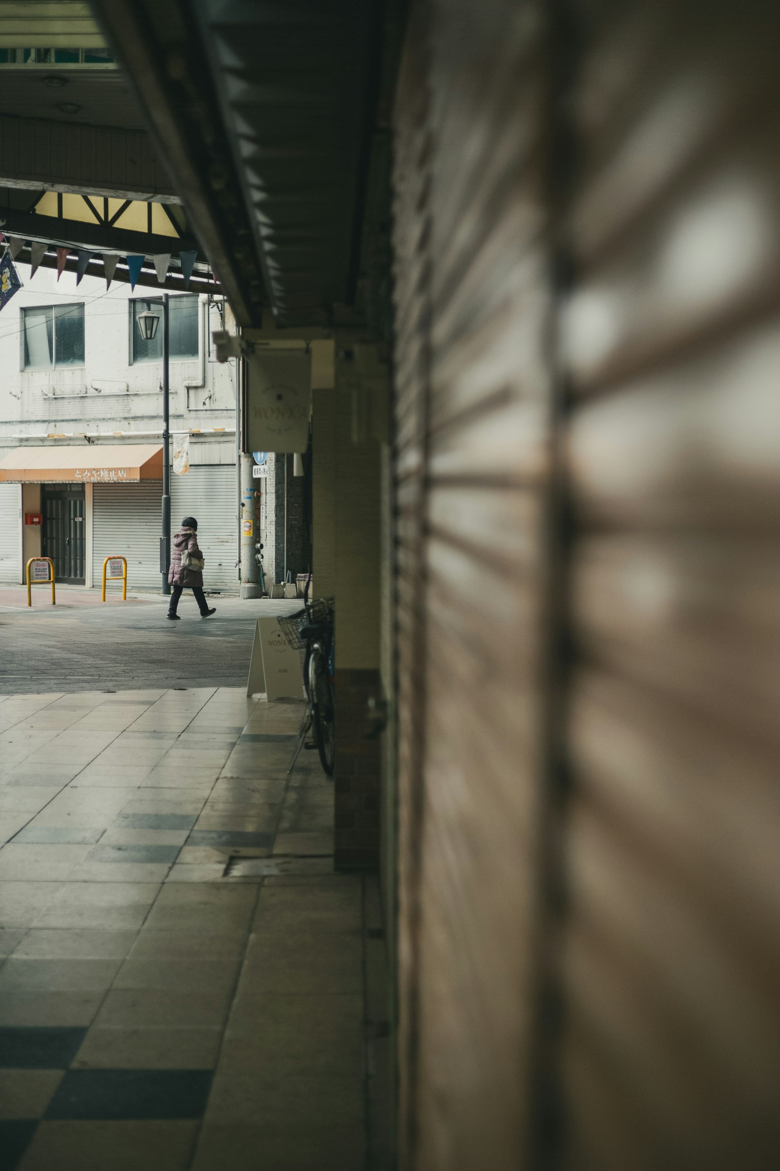Una persona caminando en una esquina tranquila con tiendas cerradas