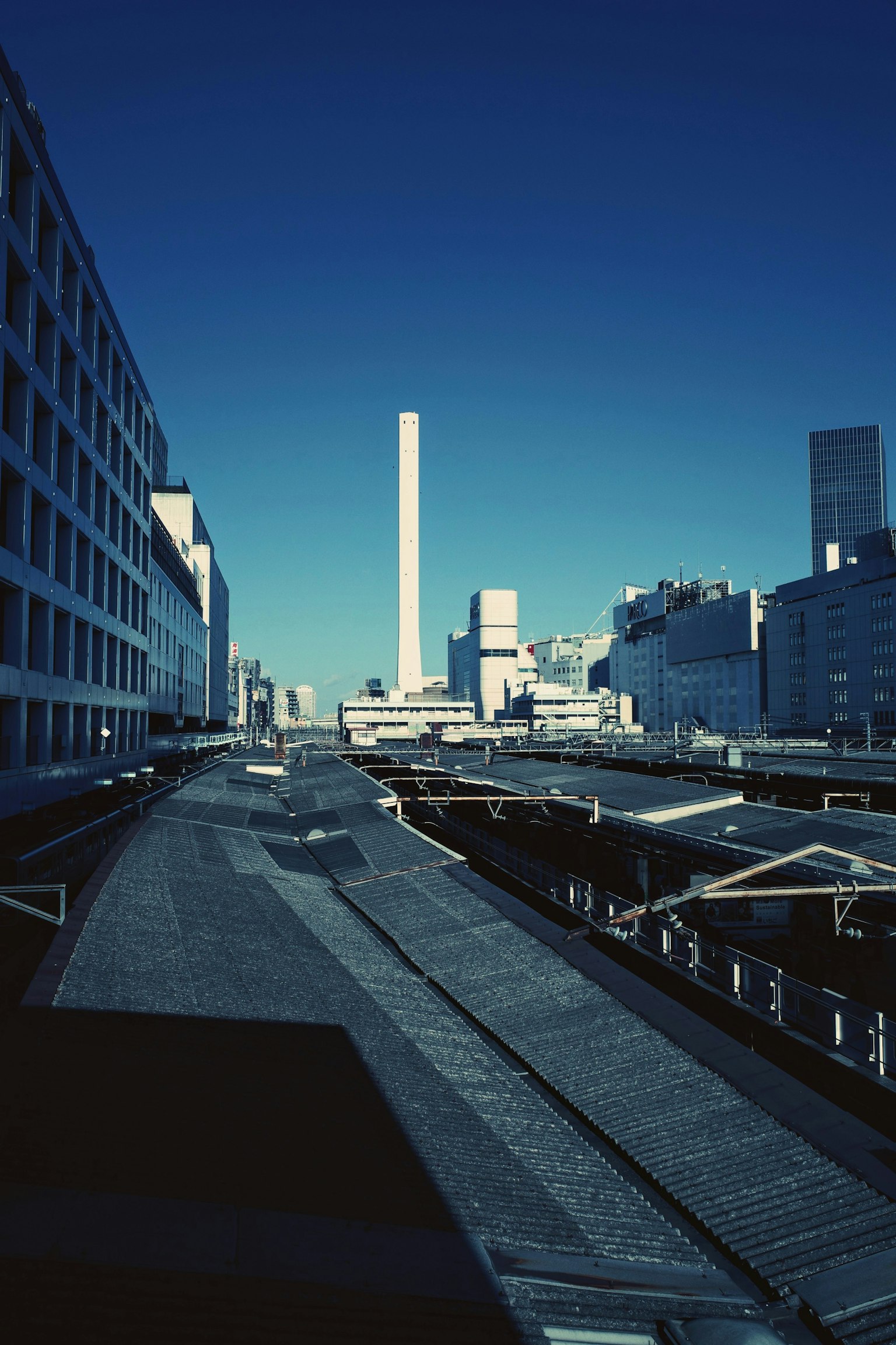 Paesaggio urbano con un alto camino e edifici moderni sotto un cielo azzurro