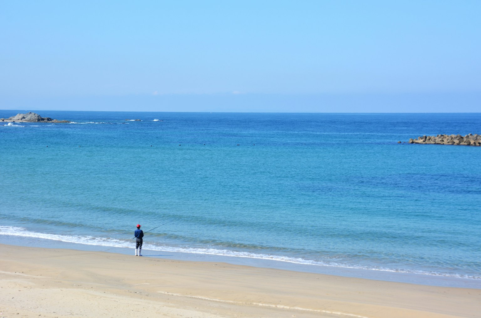 Persona de pie en una playa de arena con océano azul