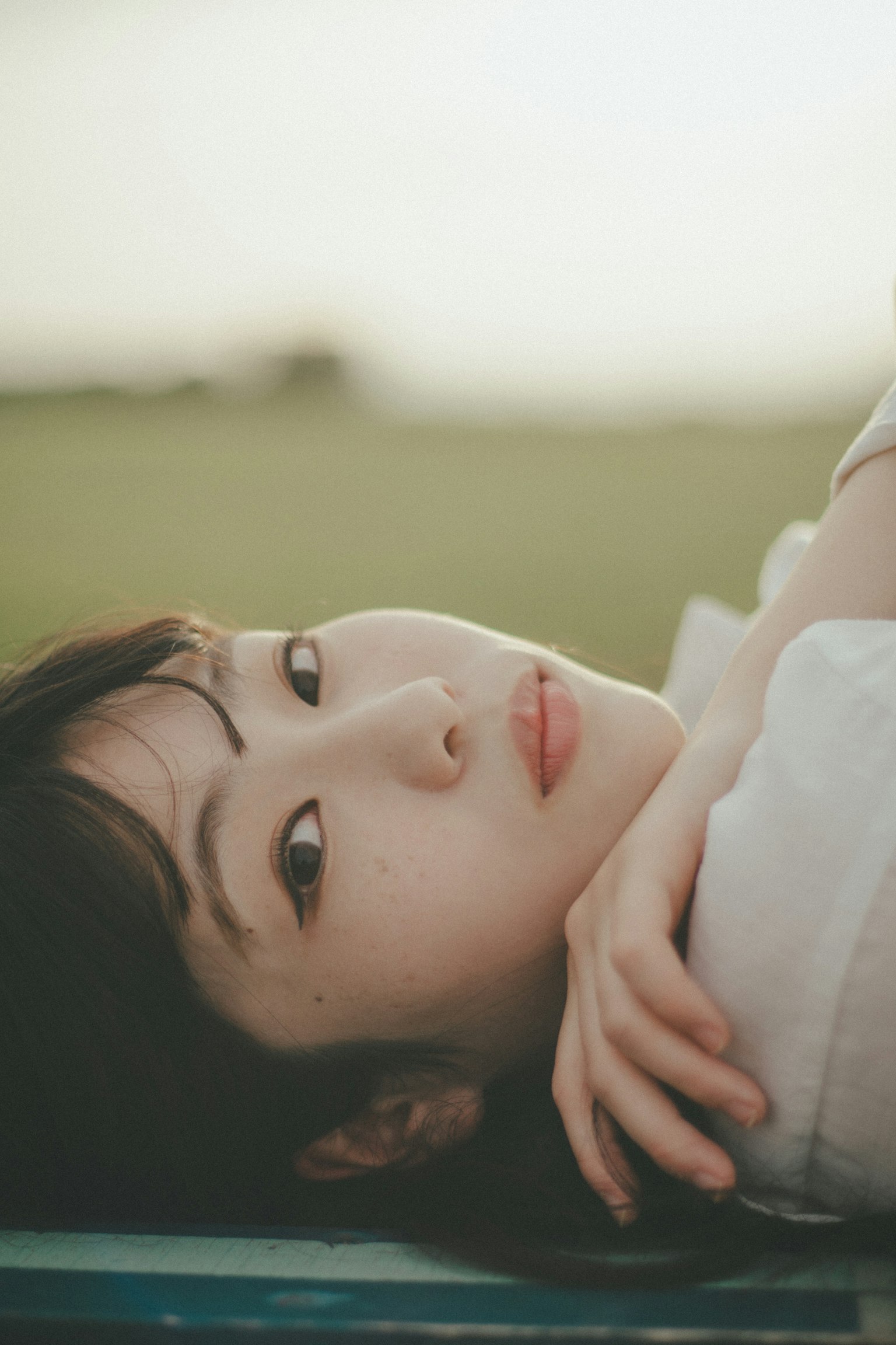 Chân dung một người phụ nữ nằm với cánh đồng xanh ở phía sau