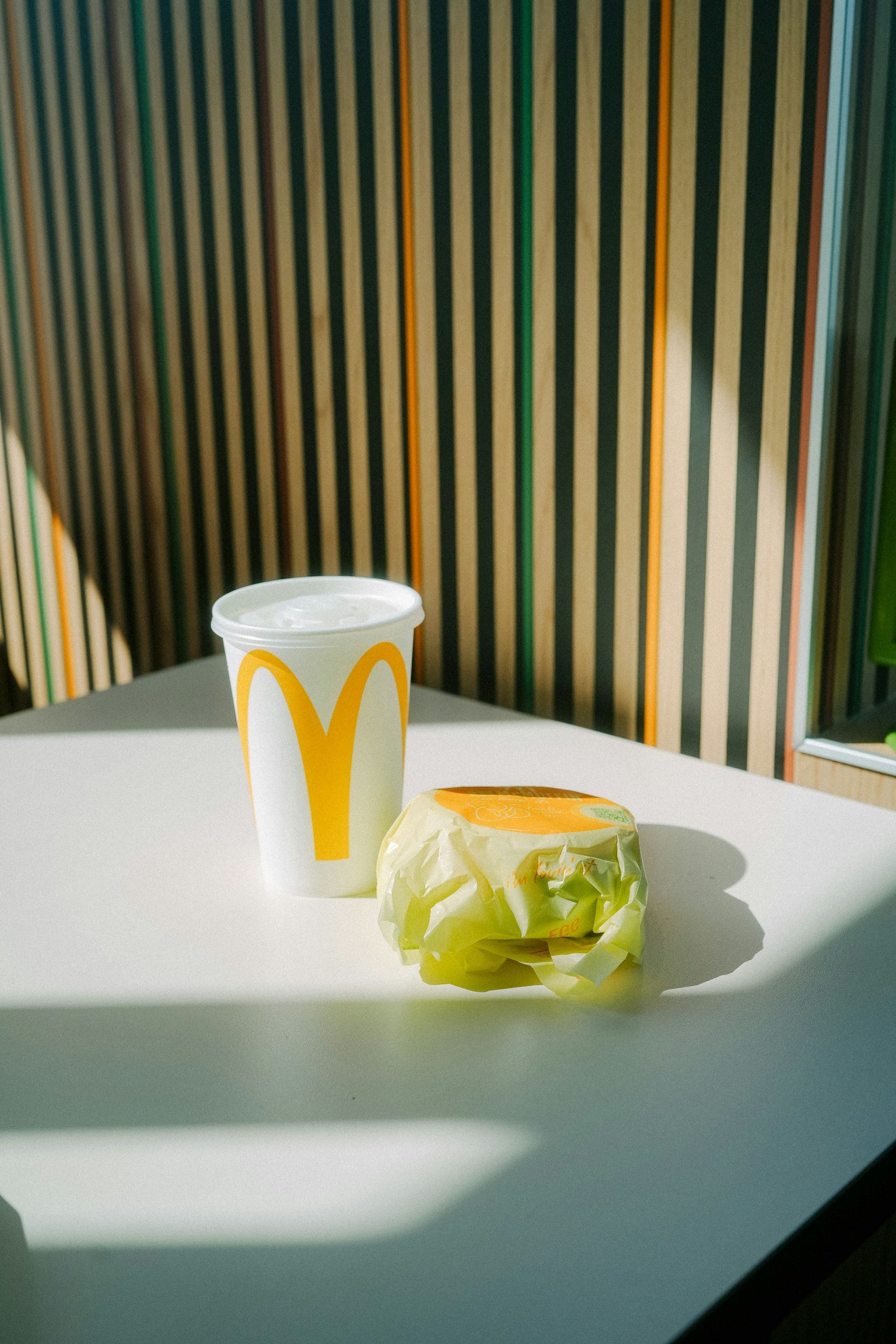 白色桌子上的麥當勞飲料杯和生菜三明治