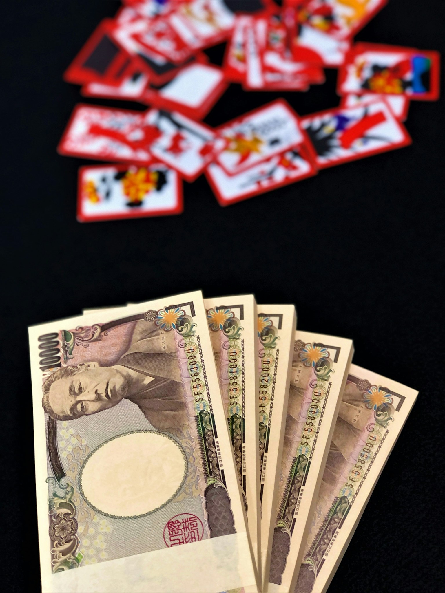 Tiền yen Nhật Bản xếp trên nền đen với một chồng thẻ đỏ