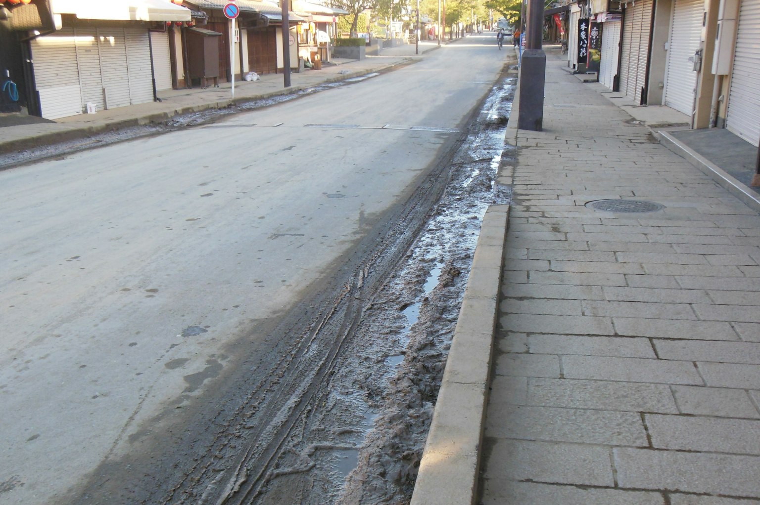 Strada vuota con pozzanghere e drenaggio lungo il marciapiede