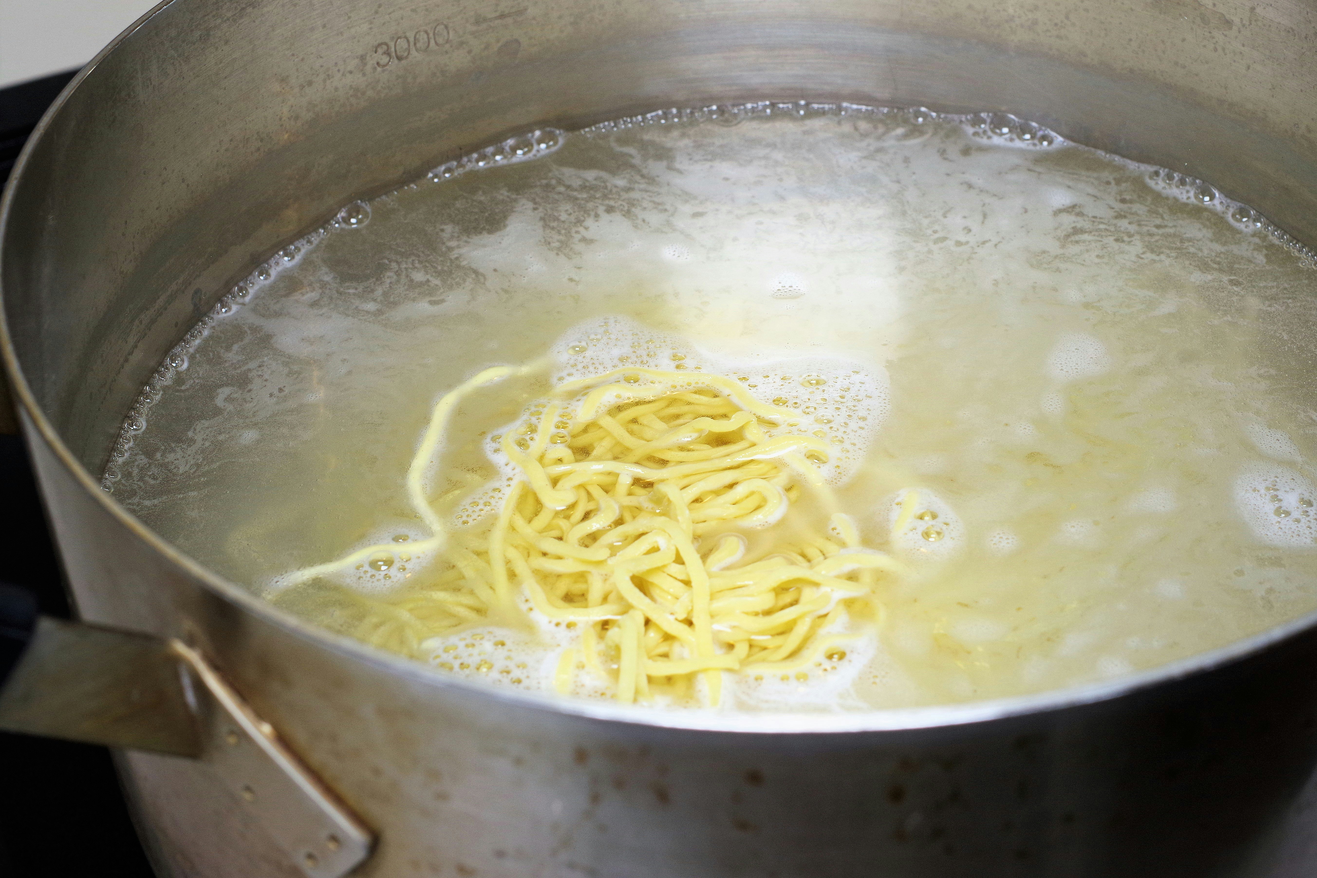鍋で茹でる麺の湯気立つ湯