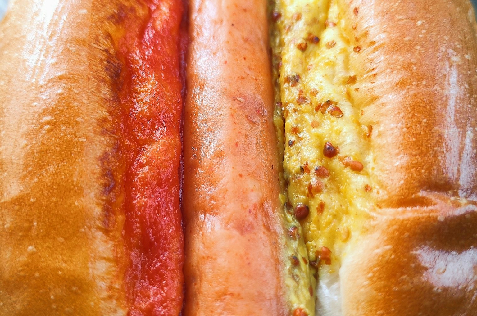 Immagine di tre hot dog allineati con salsa chili, salsa barbecue e salsa di formaggio