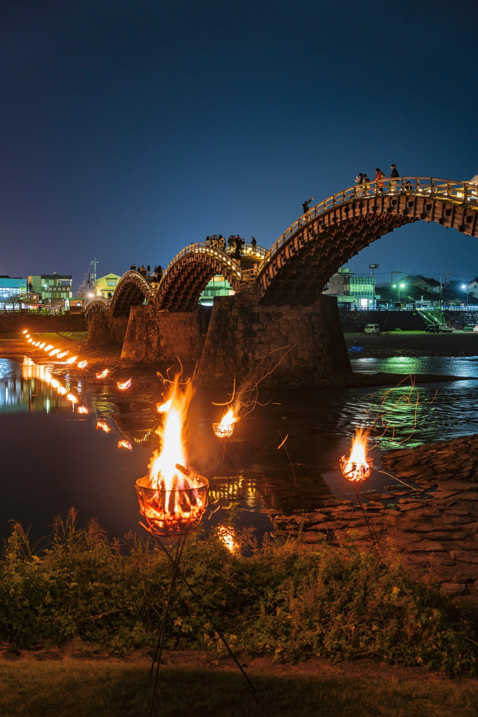 夜の錦帯橋と水面に映る火の灯り