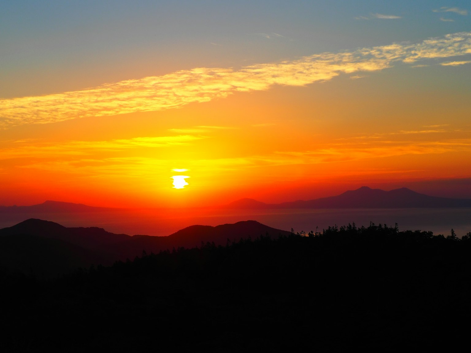 Hermoso paisaje de atardecer sol poniéndose detrás de montañas degradado naranja y azul