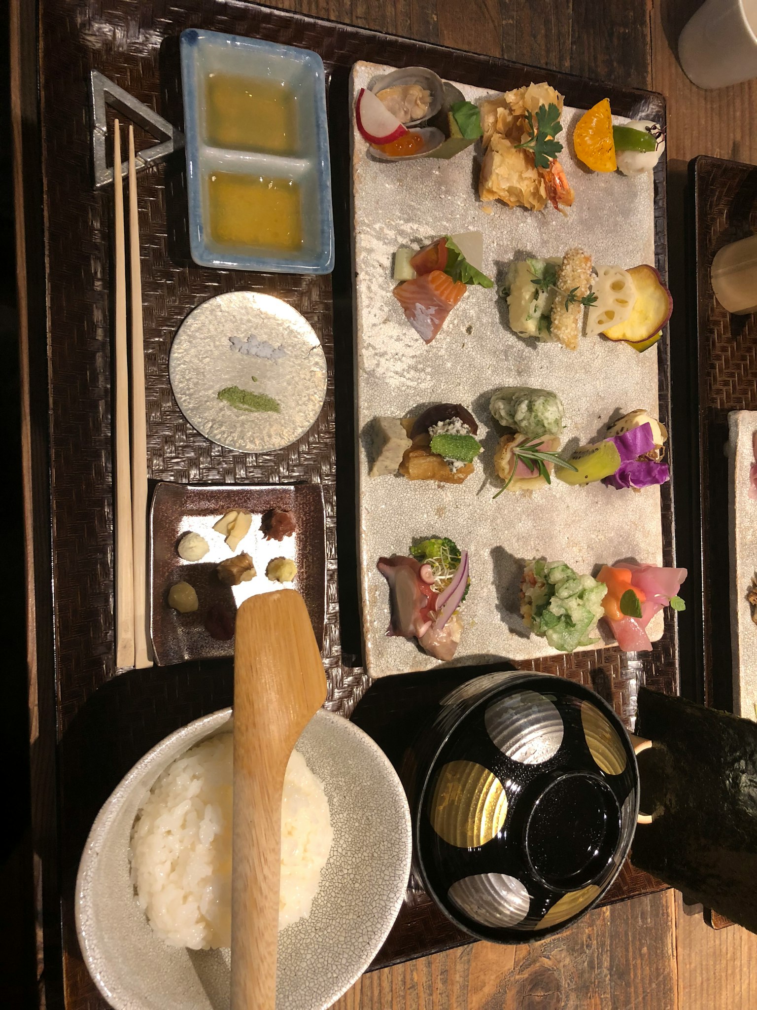 Piatto di sushi colorato con varie guarnizioni e una ciotola di riso