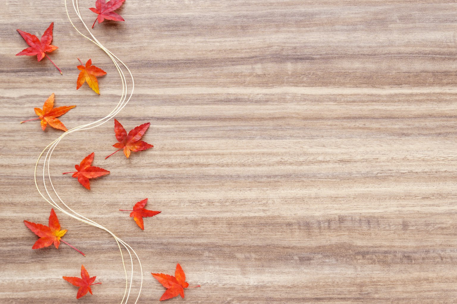 Feuilles rouges éparpillées sur une table en bois avec une ficelle