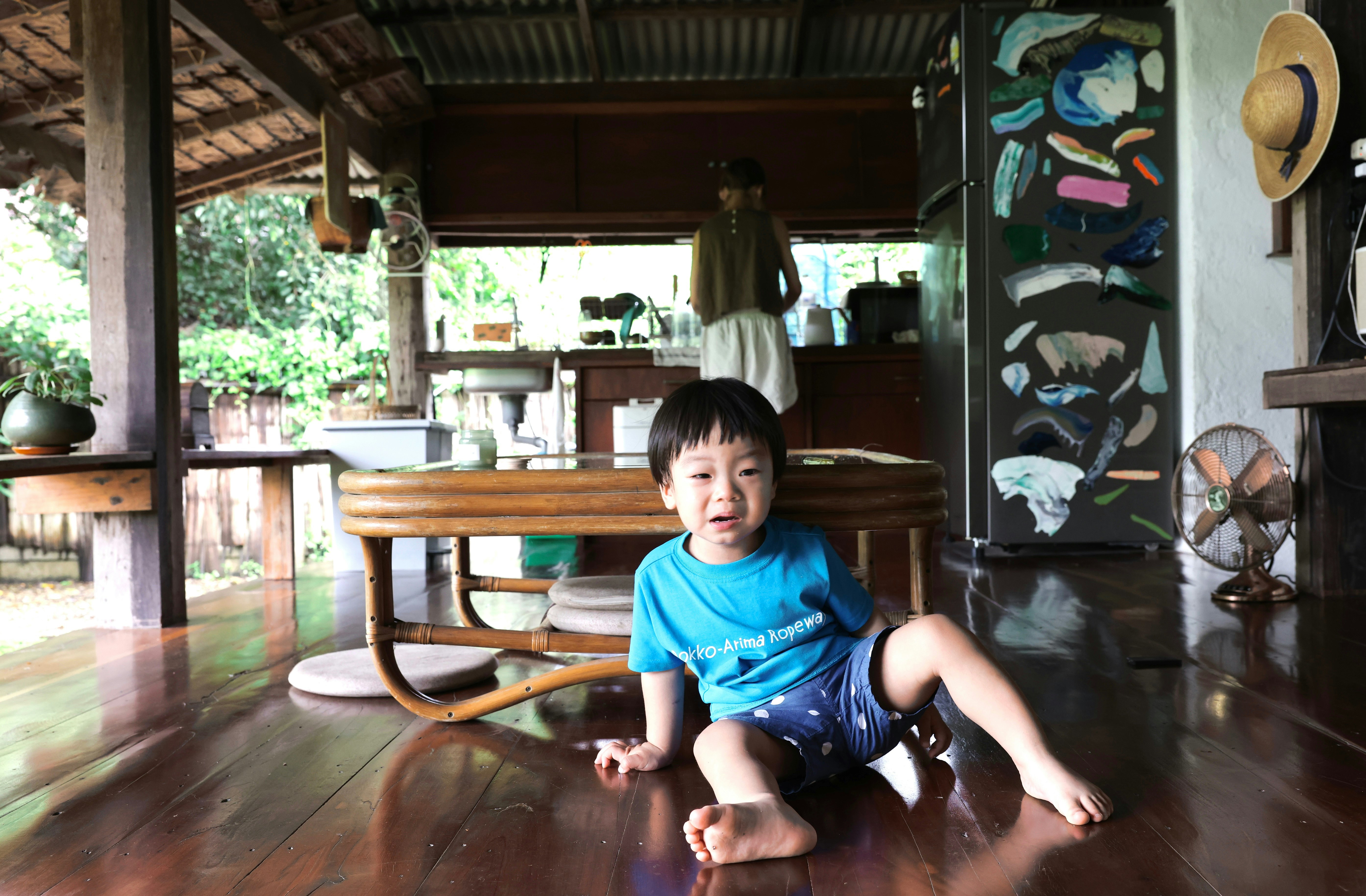木の床の室内で座る子どもの日常