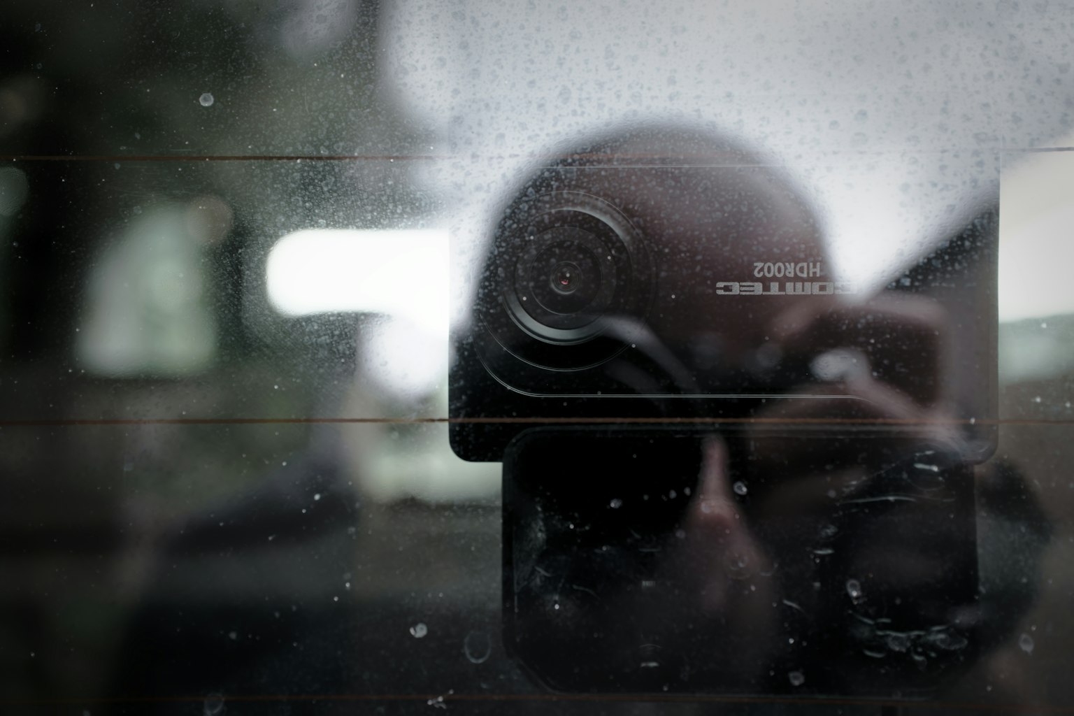 Selbstporträt, das in einem Kameralinsen durch ein beschlagenes Glas reflektiert wird