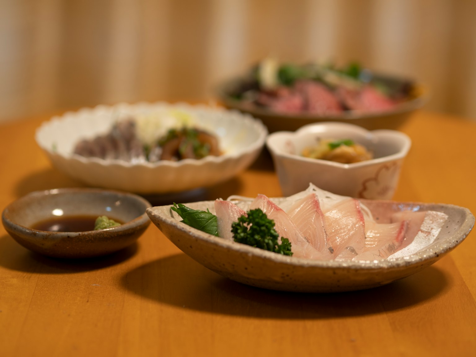 Une table avec du sashimi frais sur une assiette et divers petits plats de cuisine japonaise
