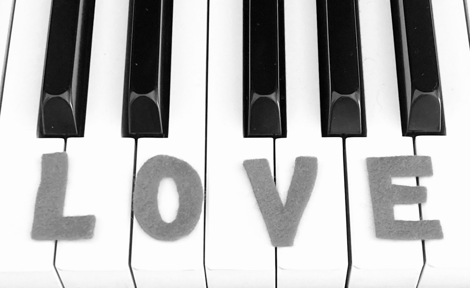 Lettere grigie che scrivono LOVE su tasti di pianoforte