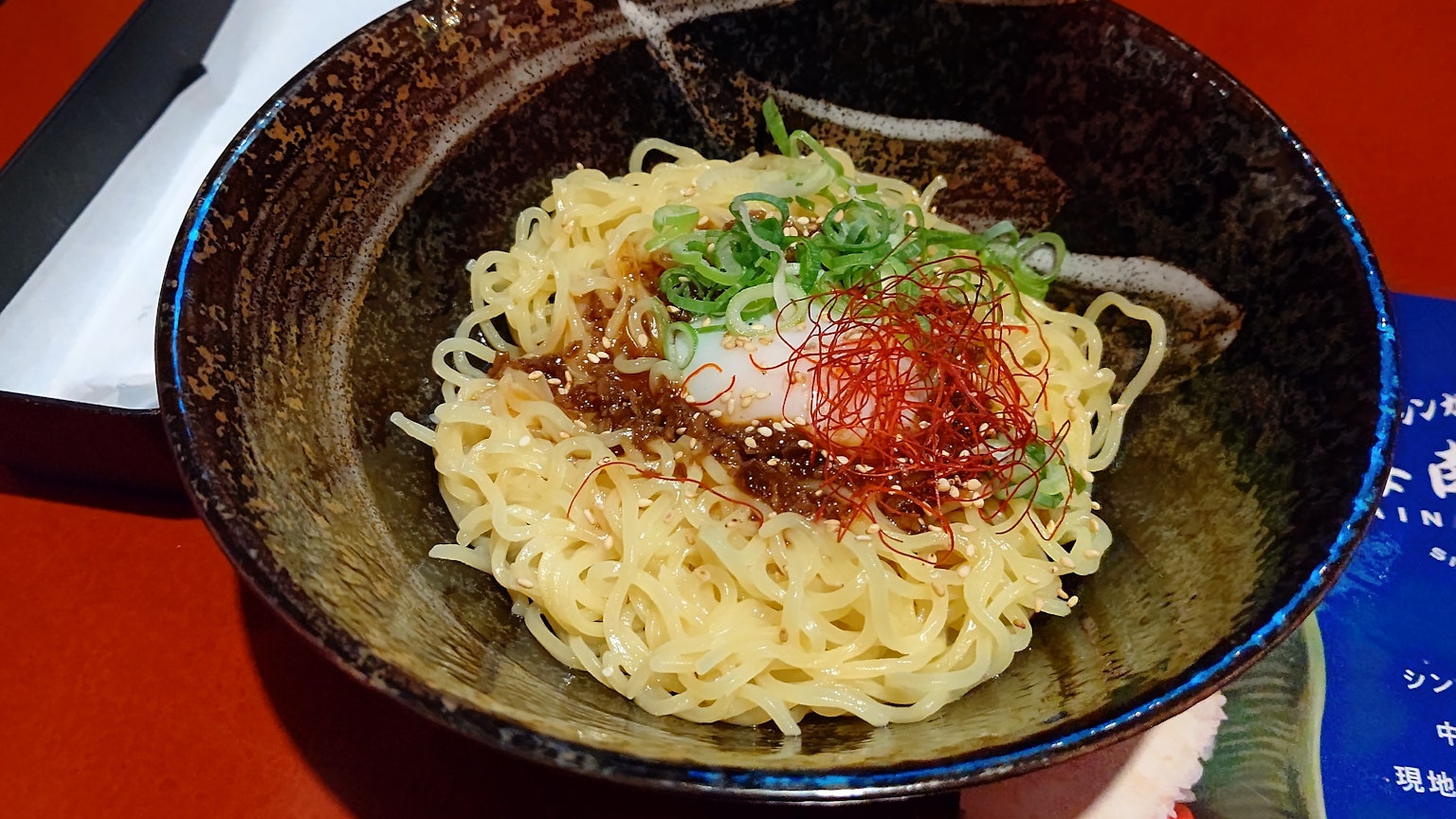 Semangkuk mie Jepang yang lezat dengan taburan daun bawang dan bumbu merah