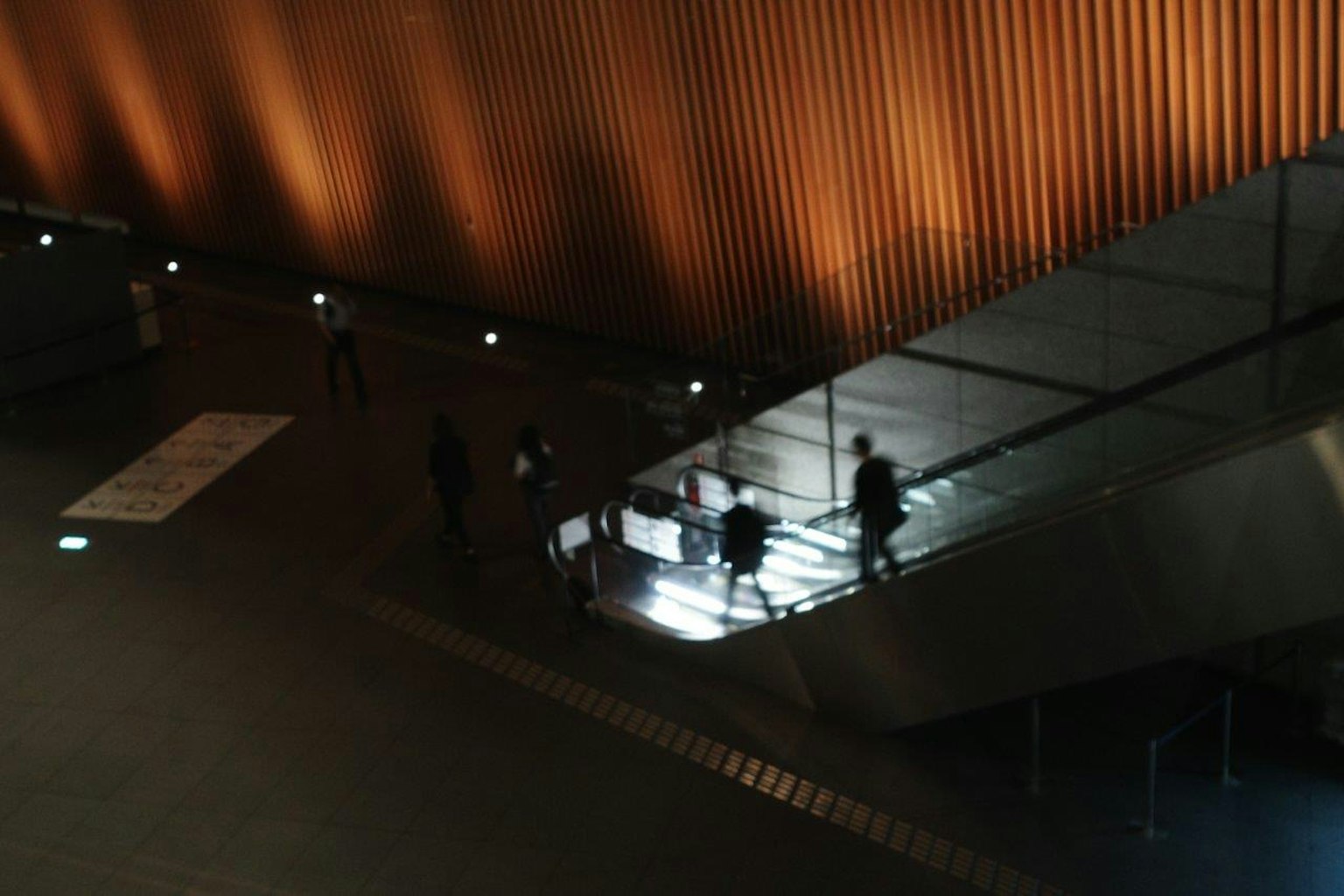 어두운 환경에서 오렌지색 벽과 함께 계단을 내려가는 사람들