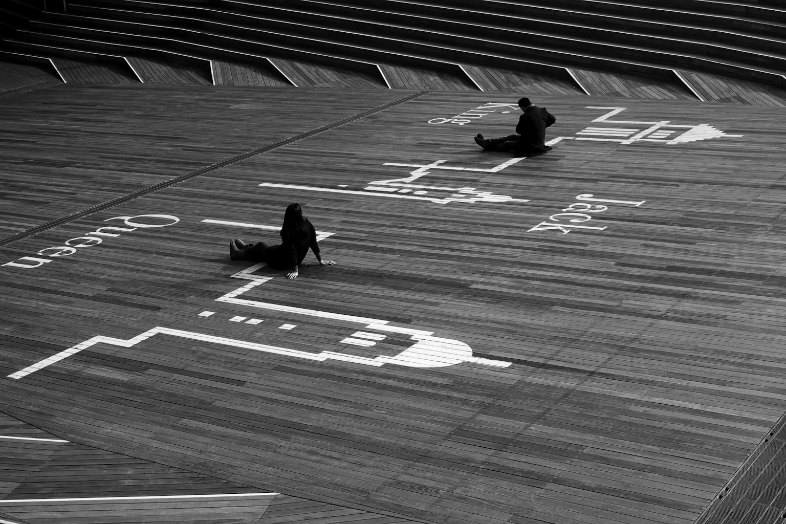 Dos figuras sentadas sobre un dibujo de línea blanca en una foto en blanco y negro