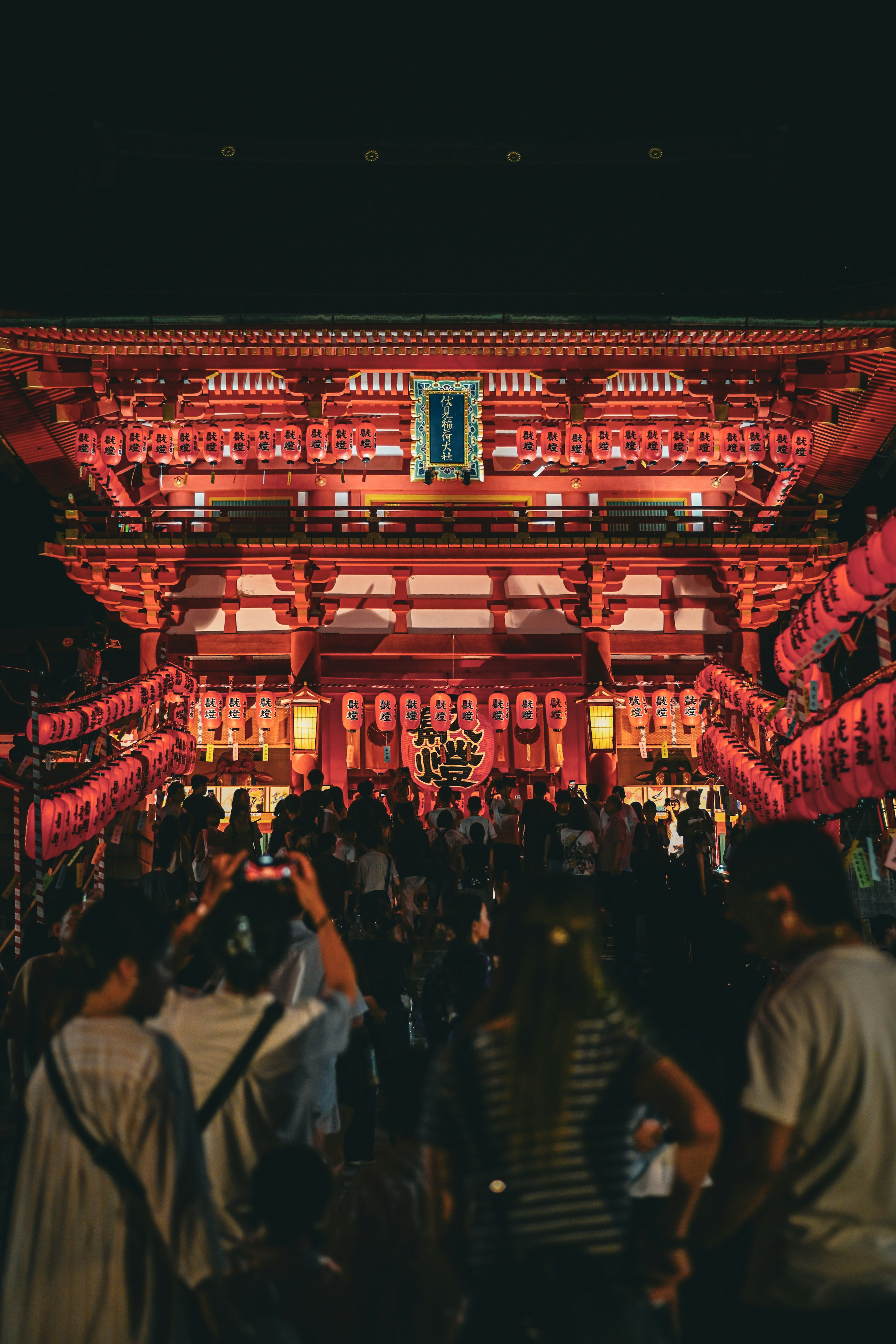 nighttime temple gate street lined with lanterns during a festival