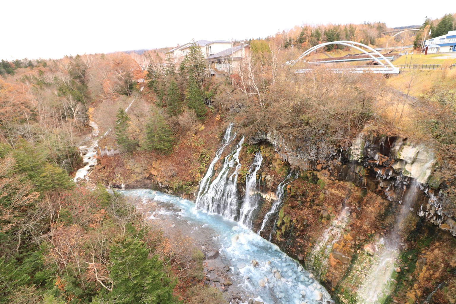 Paysage d'automne avec une cascade et une rivière pont et arbres visibles