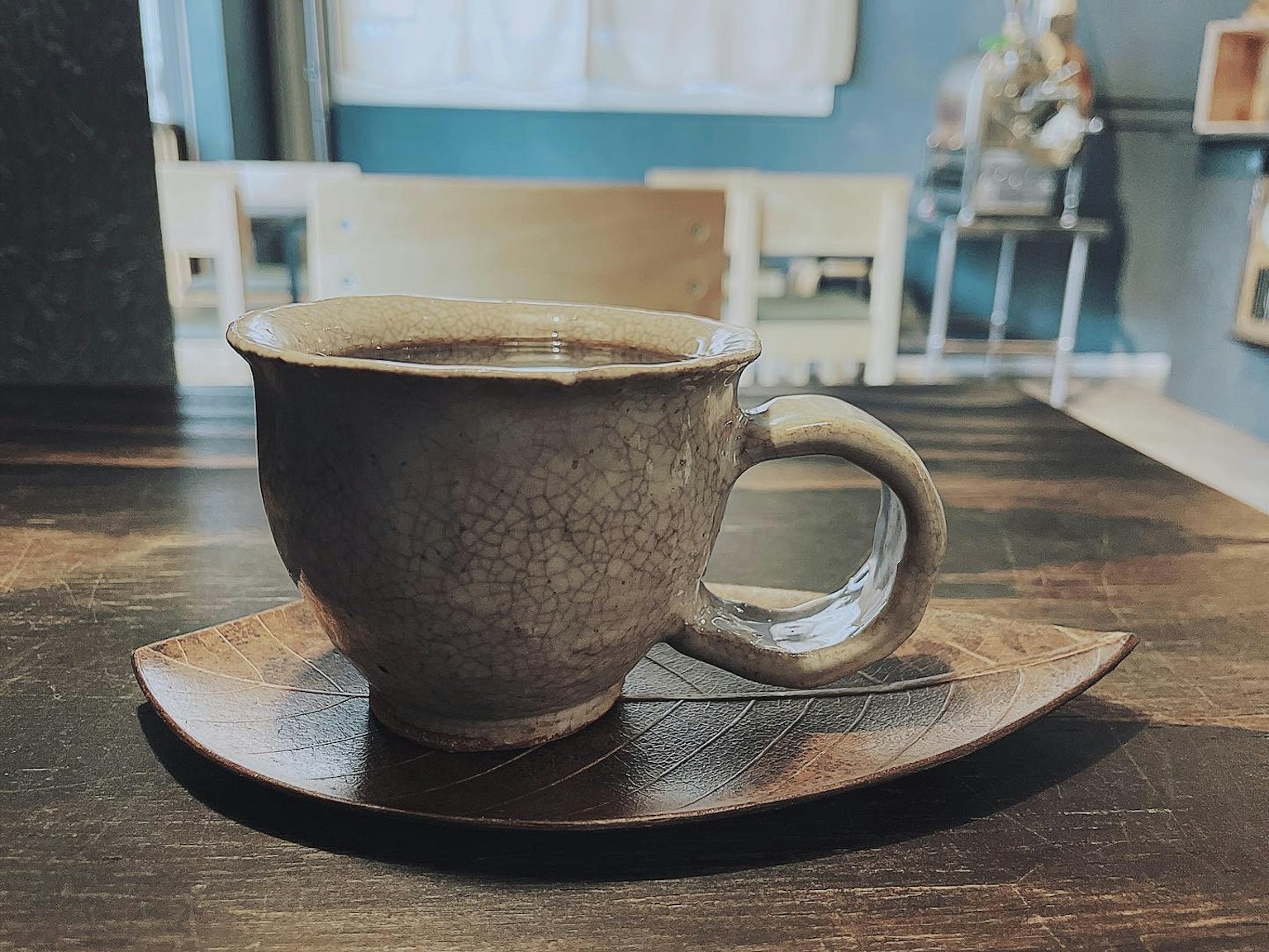 Taza de café de cerámica sobre una bandeja de madera con fondo de interior