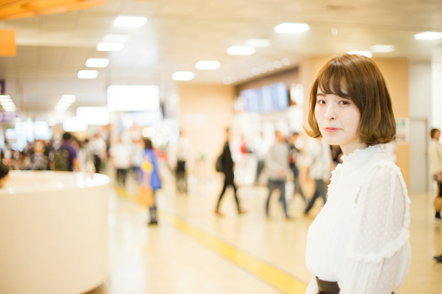 Một người phụ nữ quay lại ở ga tàu mặc áo blouse trắng với những người bận rộn ở phía sau