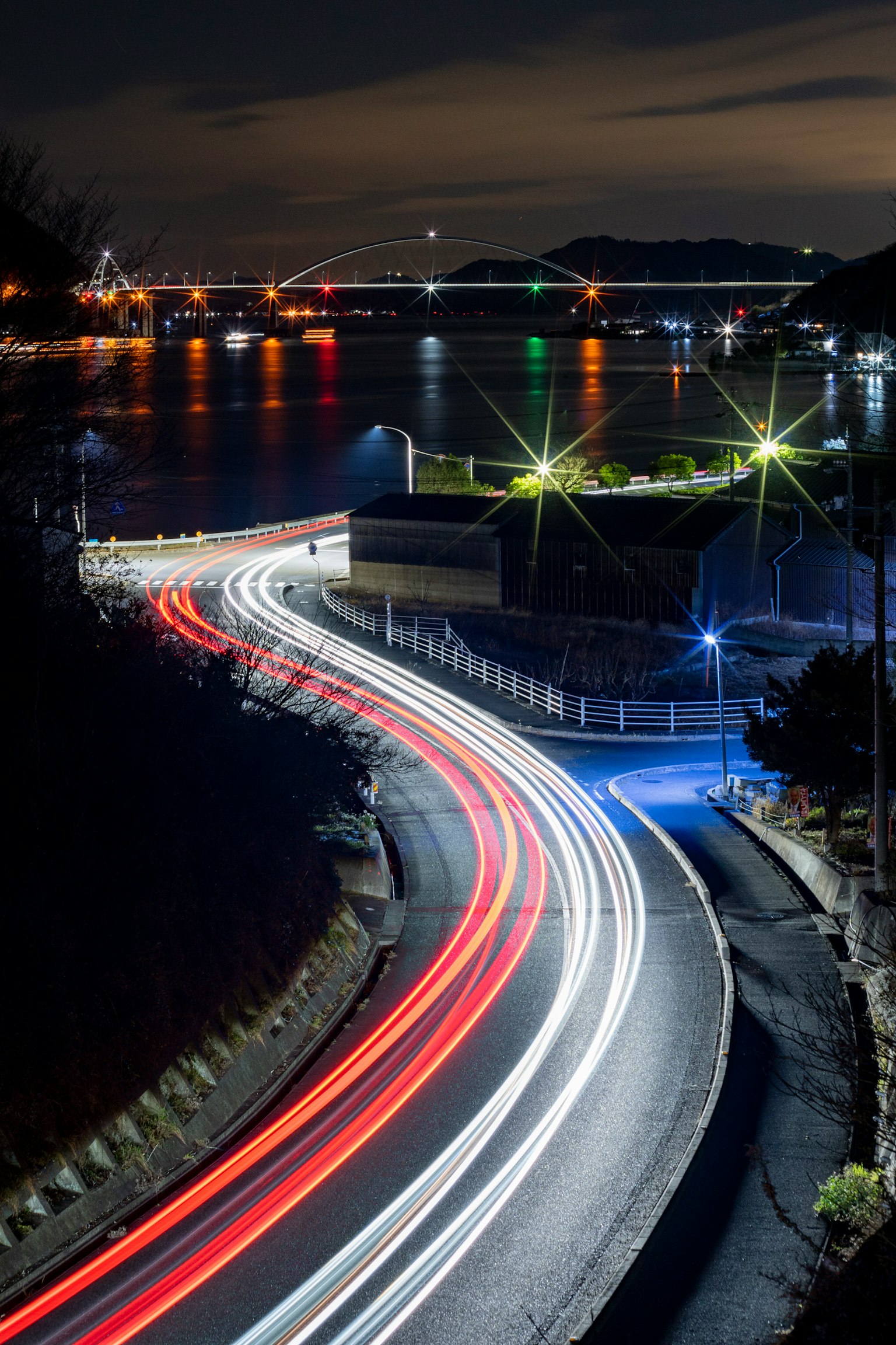 夜间沿海岸线的弯曲道路和汽车灯光