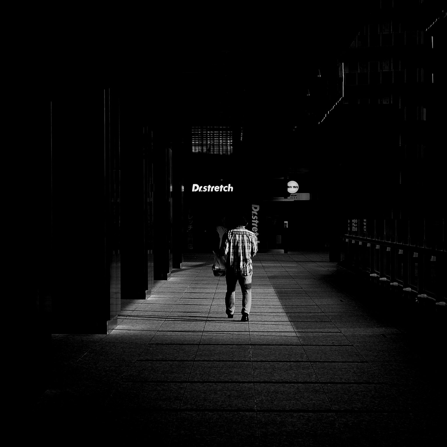 어두운 복도를 걷는 사람의 실루엣과 배경의 간판