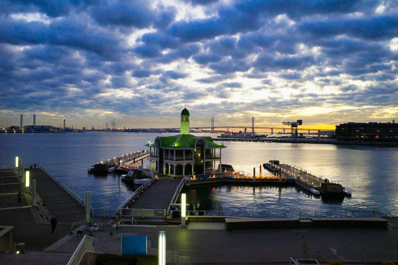 A green-roofed building on the water with a stunning sunset view