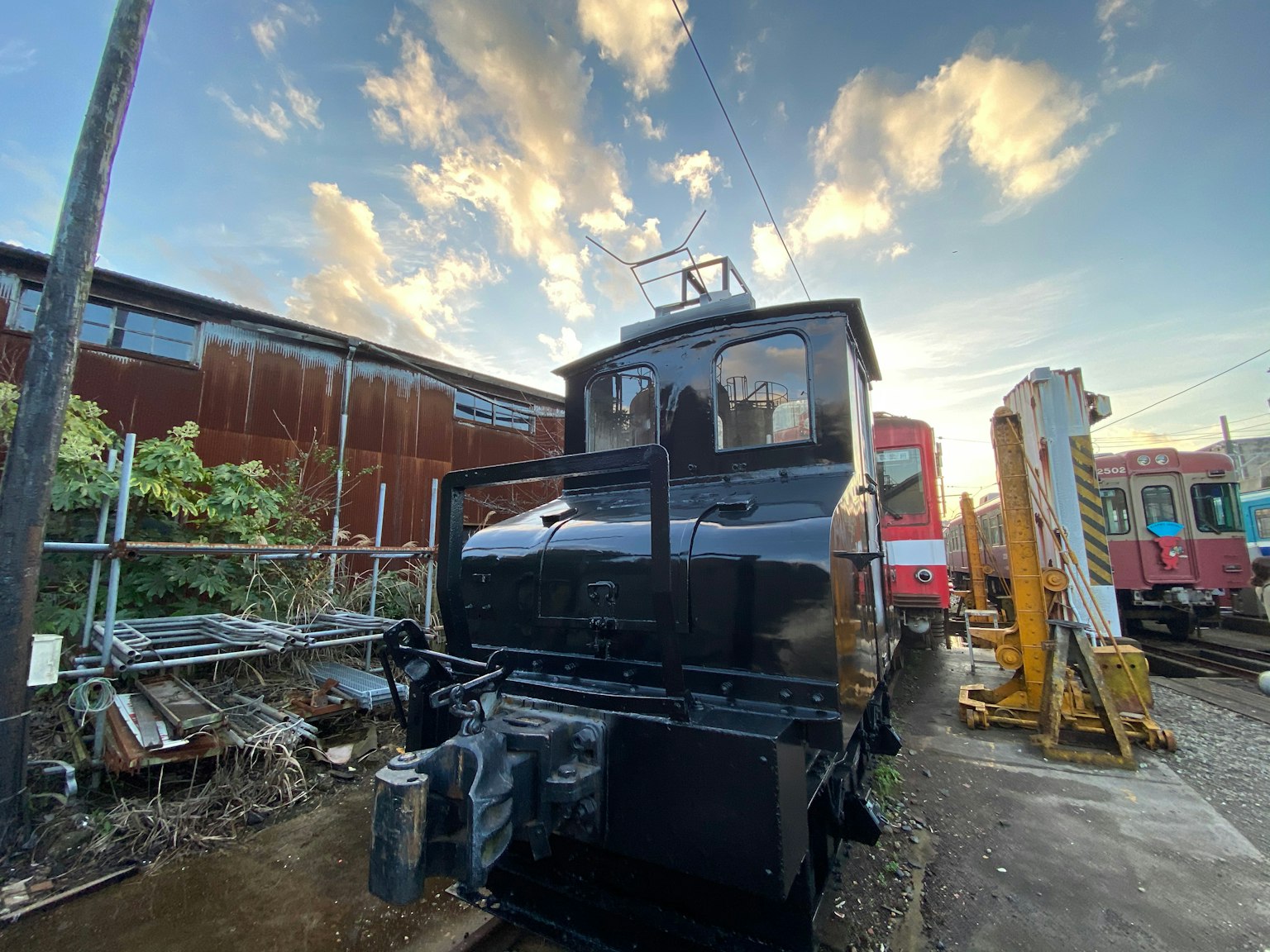 Locomotora negra bajo un cielo de atardecer con un tren antiguo al fondo
