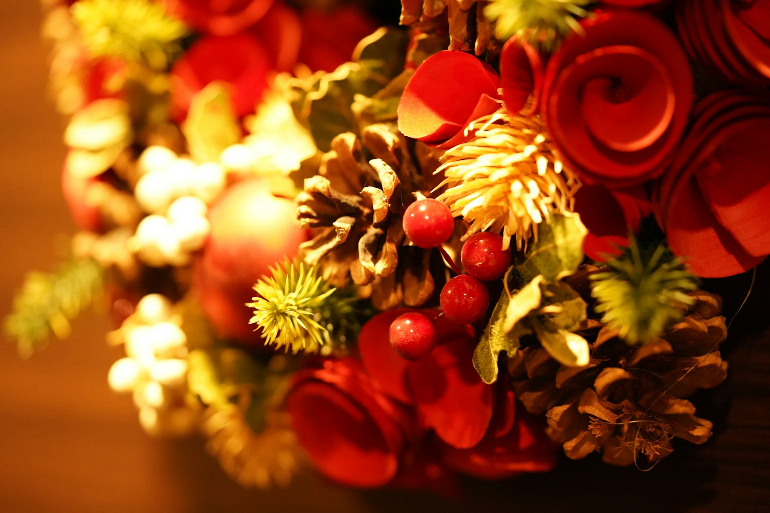 Arreglo decorativo con flores rojas y piñas